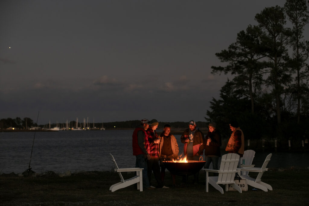 Group of campers gathered around a warm campfire at night at Camp Cardinal RV Resort.