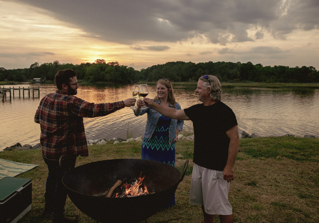 Friends enjoying wine around a firepit at Camp Cardinal.