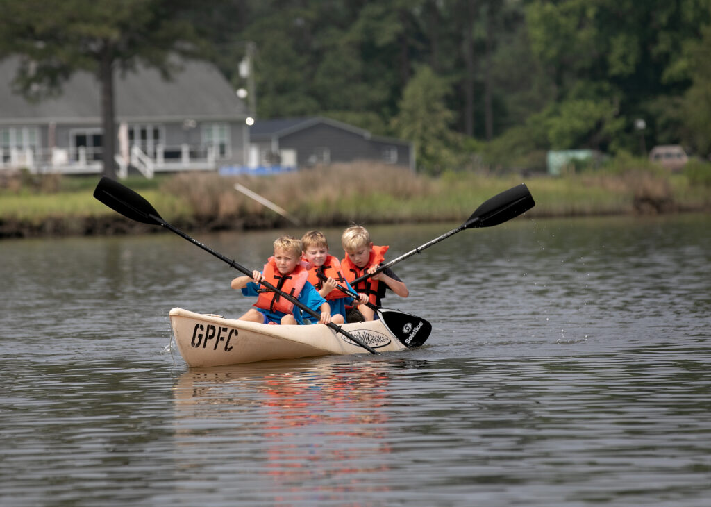 Three kids kayaking on the river in life jackets