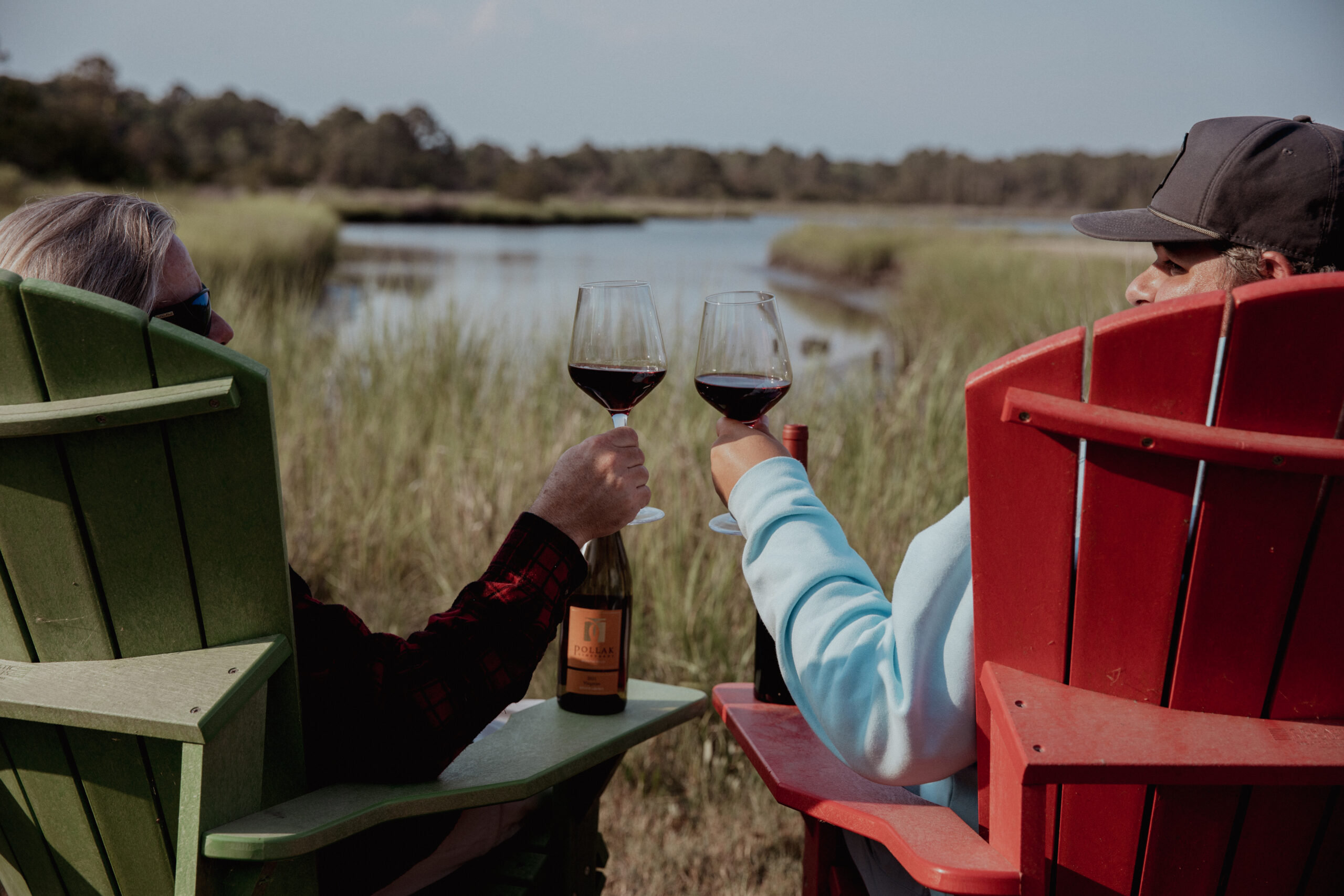 Glass of wine held up during sunset at Camp Cardinal near the river.
