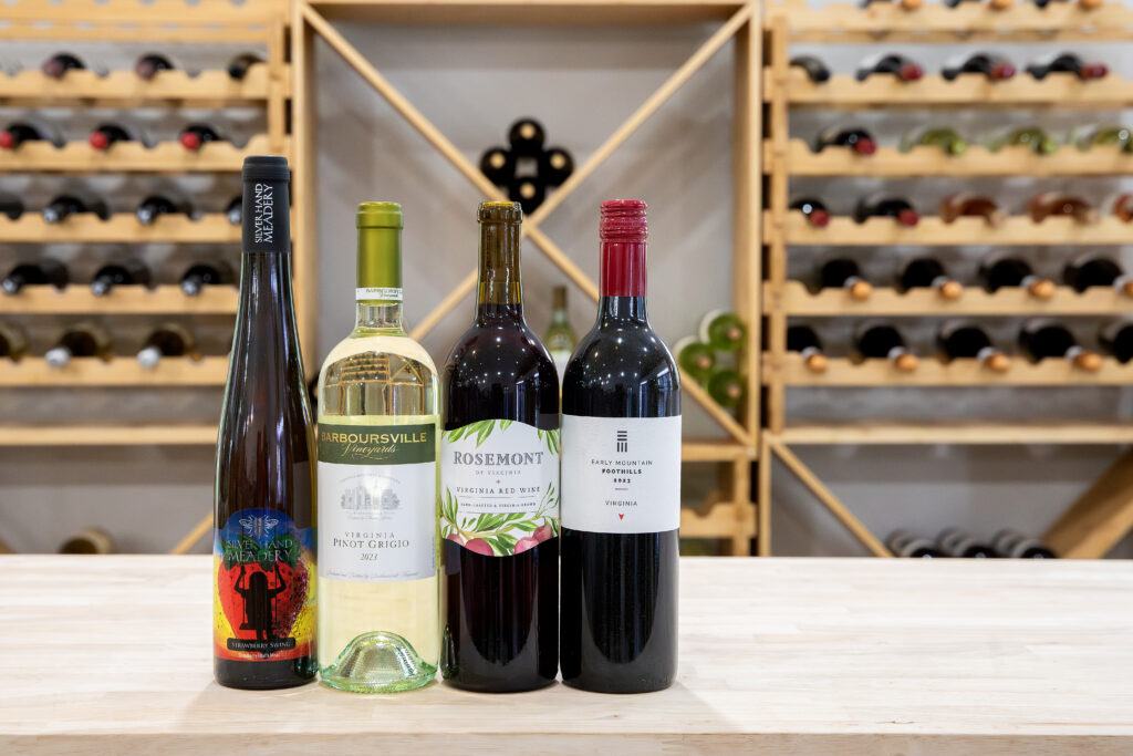 Four Virginia wine bottles displayed in front of a modern wine rack